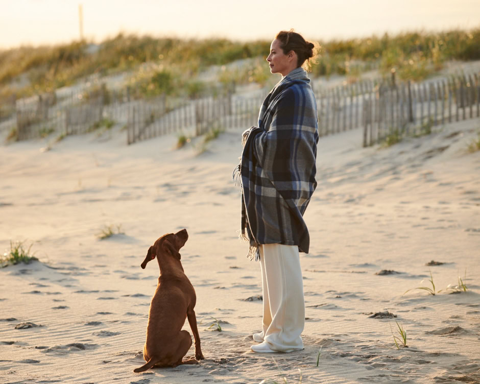 Softly dressed woman on beach with dog at sunset, fashion photography, elegant outdoor portrait, relaxed seaside scene, Pamela Hanson fashion photography.