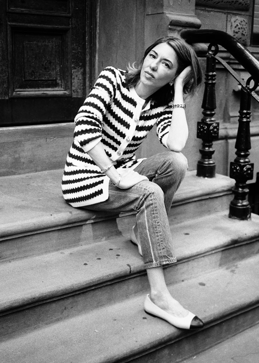 Elegant woman sitting on city stairs styled in photographer Pamela Hanson's black and white fashion portrait photography, showcasing classic timeless fashion and urban lifestyle imagery.
