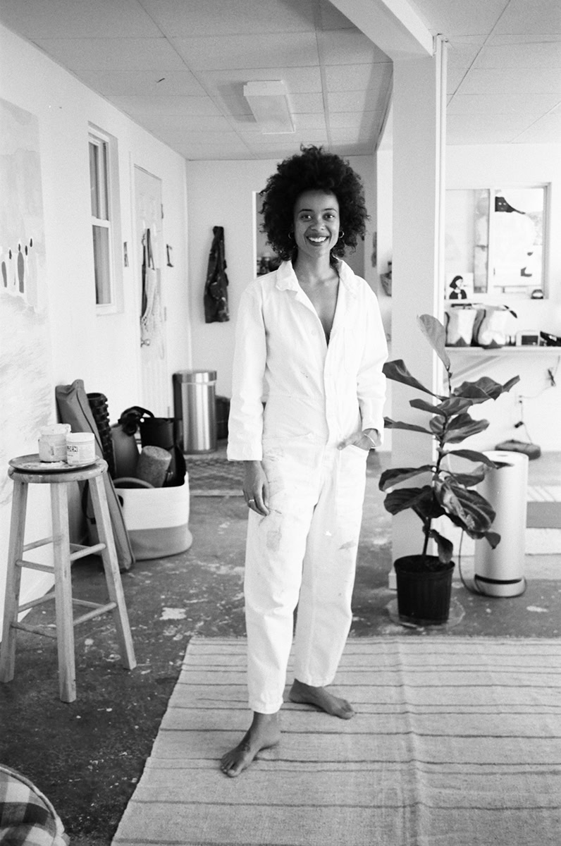 Vibrant portrait of a woman with natural curly hair in a modern art studio setting, showcasing contemporary photography by Pamela Hanson.