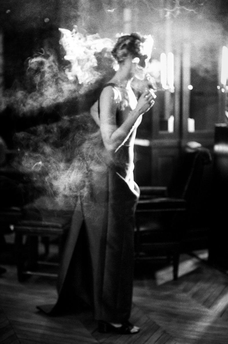 Elegant black and white portrait of a woman smoking, capturing a moody and atmospheric scene with dramatic lighting at Pamela Hanson Photography.