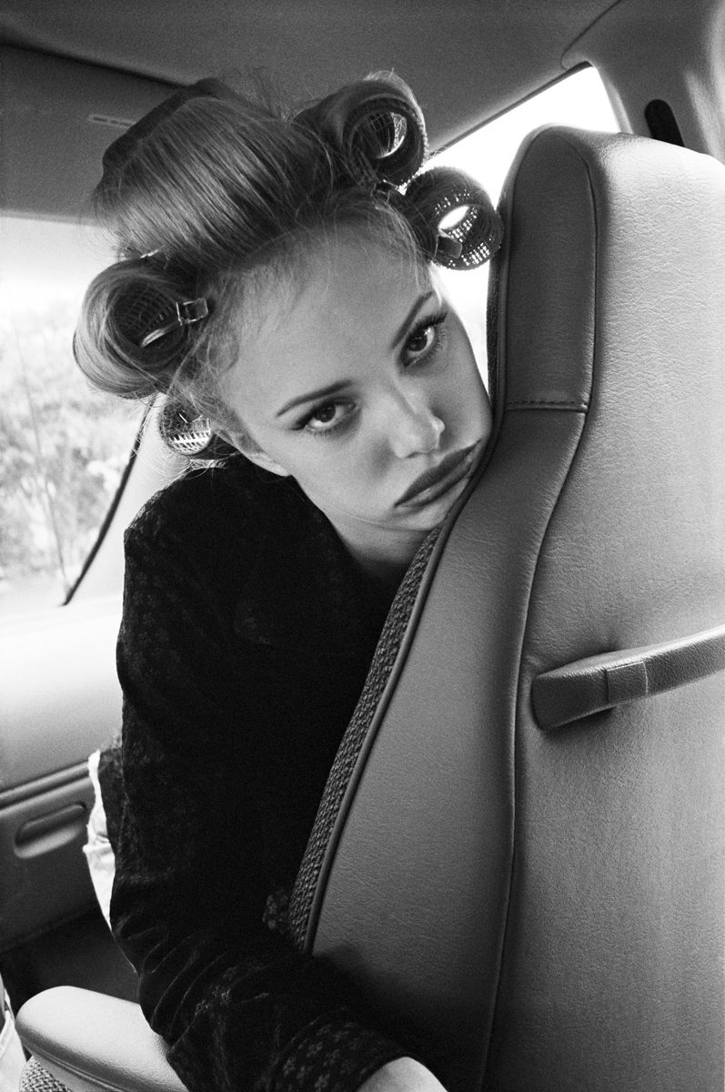 Elegant black and white portrait of a woman with vintage hair rollers, posing inside a car for a fashion and beauty photography shoot by Pamela Hanson Photography.
