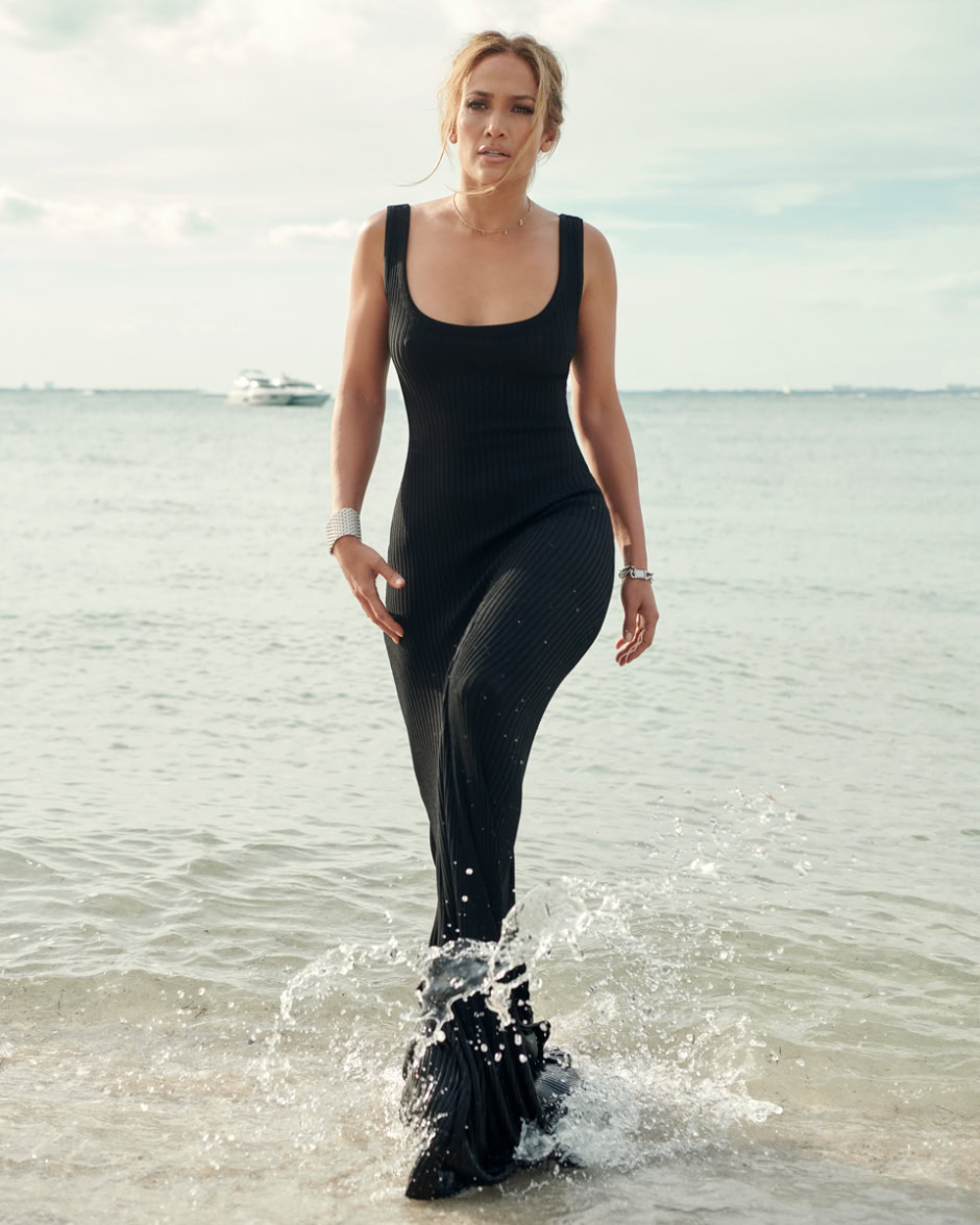 Elegant woman walking through the shallow ocean water in a black dress, showcasing lifestyle and fashion photography by Pamela Hanson.