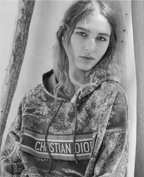 Fashion photography of a young woman wearing a Christian Dior hoodie, natural light, black and white portrait, fashion model, casual street style, artistic black and white photography, modern fashion shoot, editorial style, professional fashion photography.