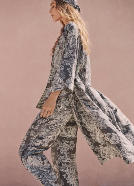 Elegant woman wearing stylish monochrome printed loungewear set, standing against soft pink background, showcasing fashion photography by Pamela Hanson.