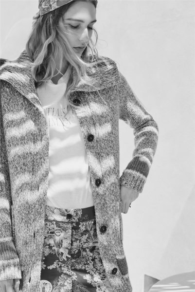 Stylish woman wearing a patterned knit cardigan and floral pants, showcasing fashion photography by Pamela Hanson in black and white, emphasizing casual yet chic fashion styling.