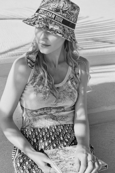 Elegant black and white portrait of a woman wearing a Christian Dior bucket hat, stylish patterned clothing, and holding a fashion magazine, showcasing Pamela Hanson Photography's focus on fashion and portrait photography.