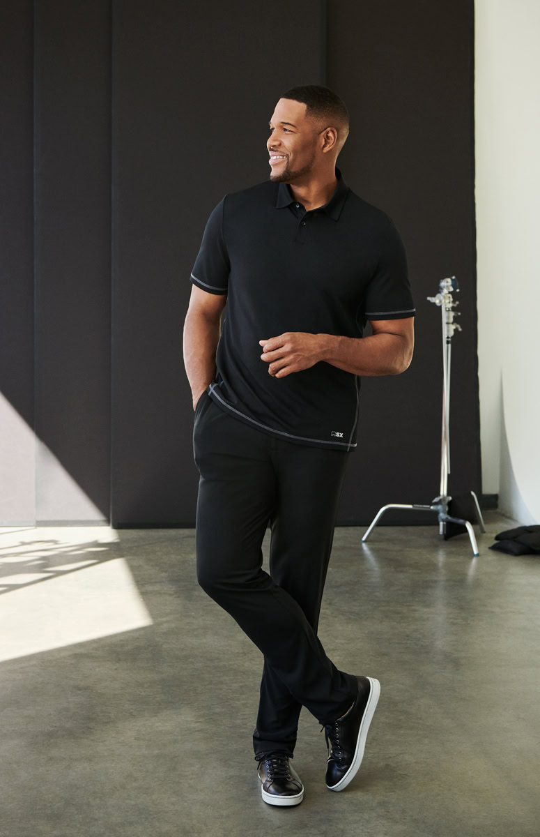Affordable men's fashion portrait by Pamela Hanson Photography, showcasing a smiling man in casual style, modern black polo shirt and joggers, in a professional studio setting.