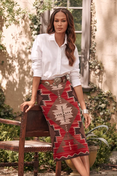 Elegant woman in white blouse and tribal patterned skirt outdoors, fashion photography, natural light, stylish and sophisticated look, Pamela Hanson Photography, desert garden setting, fashion portrait, bohemian style elements, high-end fashion imagery, editorial fashion photography.