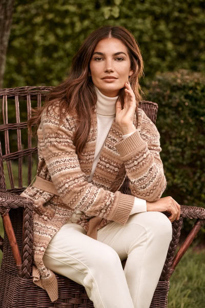 Elegant portrait of a young woman seated outdoors, wearing a cozy knit cardigan and white turtleneck, captured by Pamela Hanson Photography, showcasing style, natural beauty, and outdoor fashion photography.