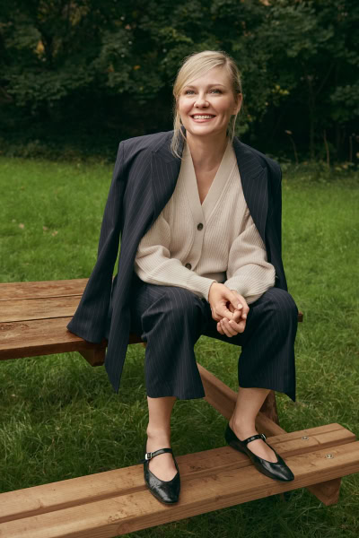 Elegant woman in business casual attire sitting outdoors on a wooden bench, showcasing portrait photography for Pamela Hanson Photography.
