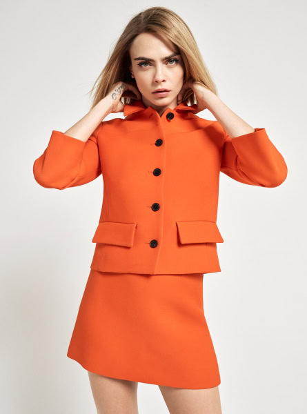 Stunning fashion portrait of a young woman in an orange blazer and matching skirt, showcasing Pamela Hanson's high-fashion photography and editorial styling.