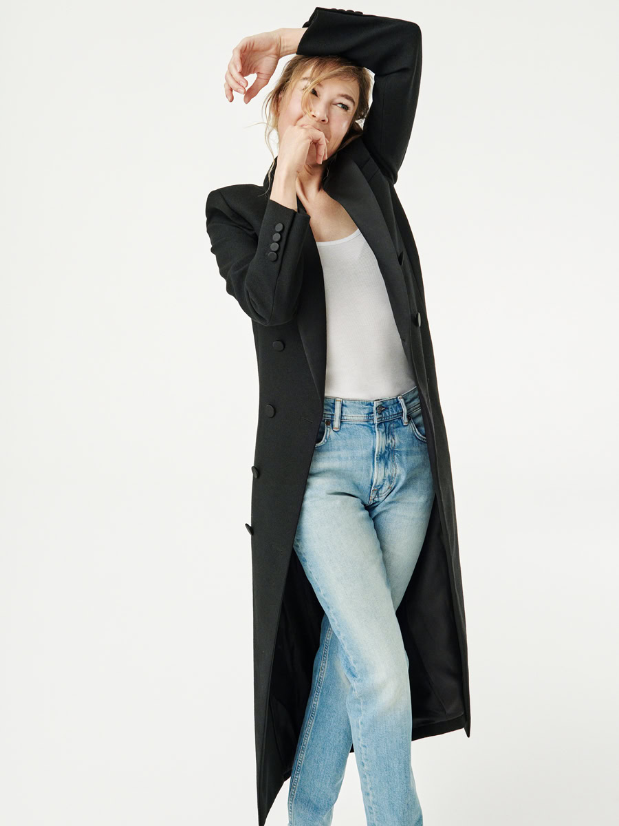 Modern fashion portrait of a young woman in casual jeans and a black blazer, expressive pose, professional photography by Pamela Hanson, stylish lifestyle photography, bright minimalist background.