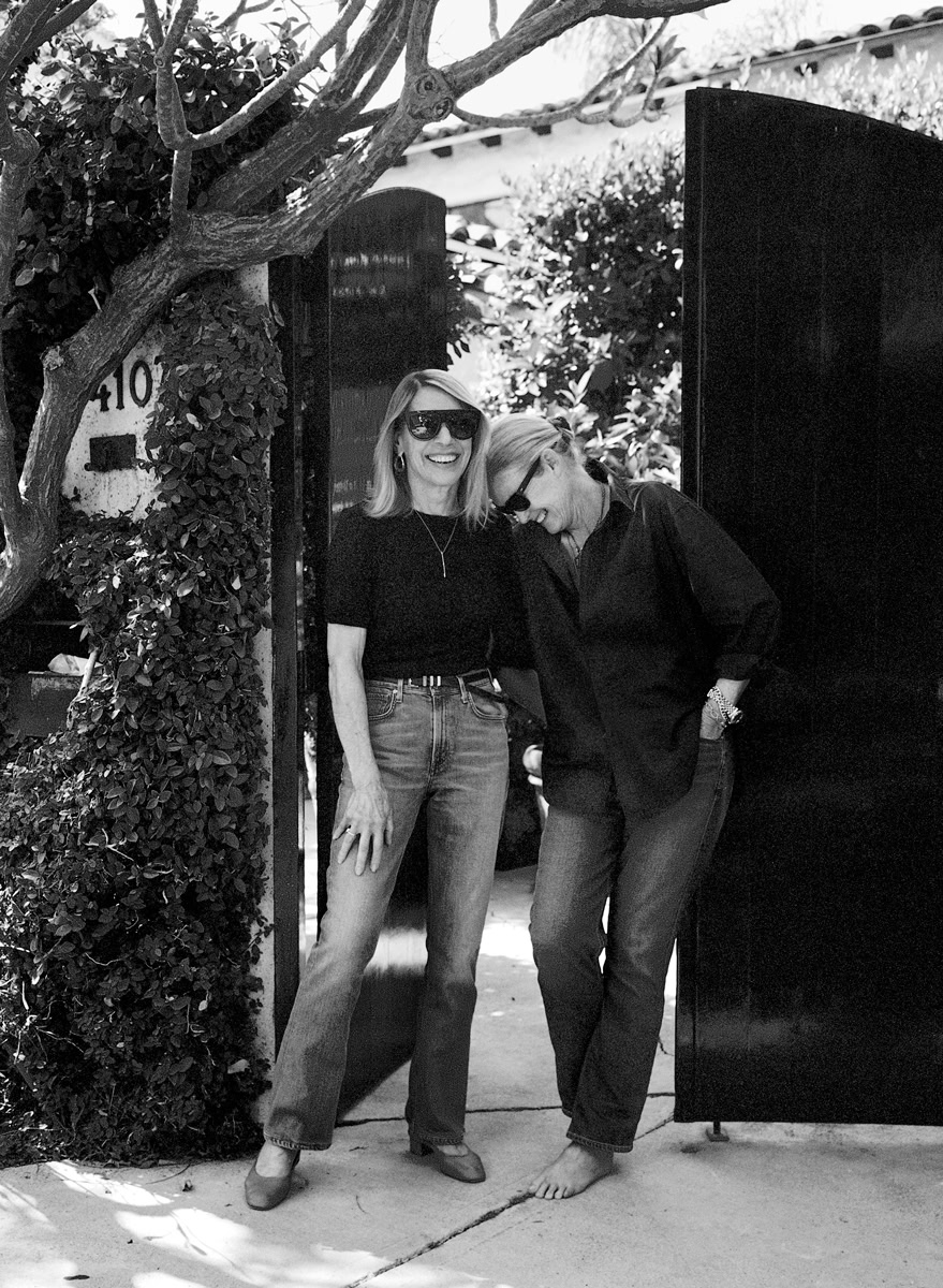 Women smiling and laughing outdoors in a candid black and white portrait, capturing natural beauty and authentic moments, showcasing Pamela Hanson photography skills.