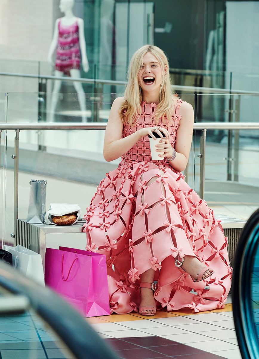 Young woman in pink designer dress laughing while sitting on bench at shopping mall, holding coffee cup, with shopping bags and snacks nearby, showcasing contemporary fashion photography, retail lifestyle, and candid moments, captured by Pamela Hanson Photography.