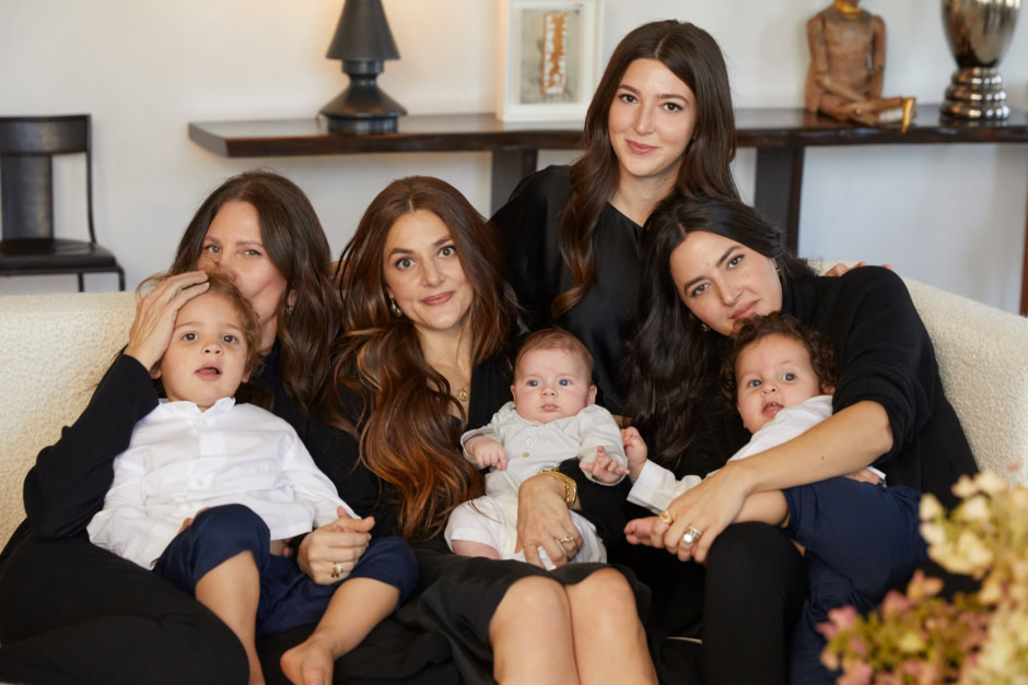 Family portrait of four women and three children sitting on a cozy sofa in a stylish living room, showcasing Pamela Hanson Photography's focus on candid family photography, warmth, and connection.