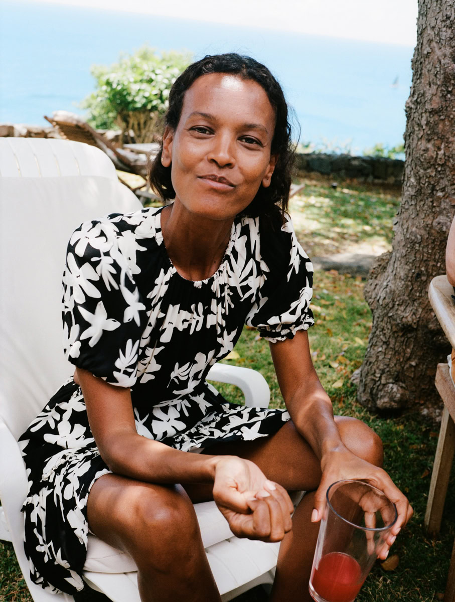 Vibrant portrait of a woman in a black and white floral dress enjoying outdoor seaside gathering, capturing candid moments and natural expressions.