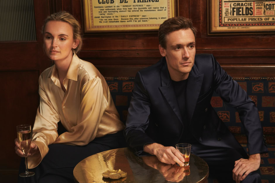Elegant couple in a vintage bar setting, with sophisticated attire and drinks, captured through Pamela Hanson photography, showcasing intimate, fashion, and lifestyle photography skills.