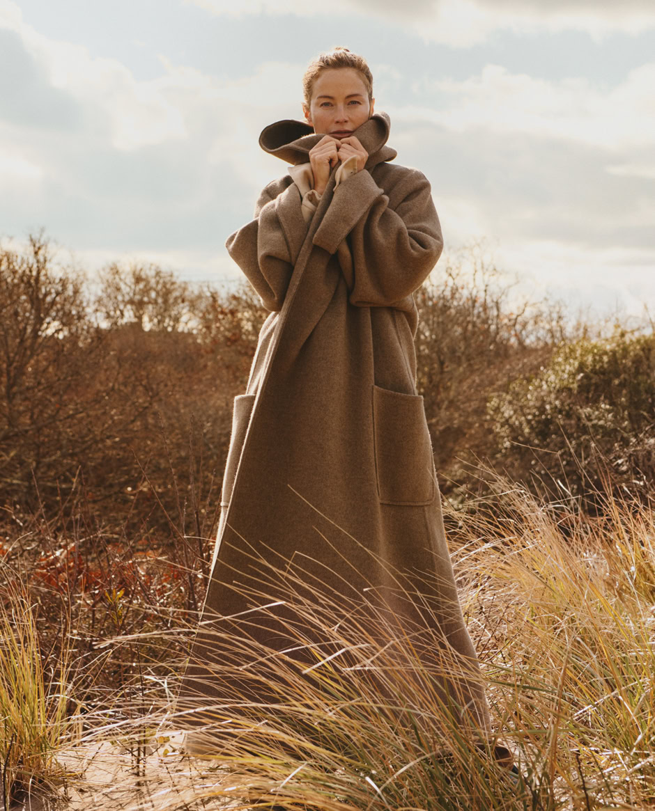 Luxurious brown wool coat fashion photography by Pamela Hanson featuring an elegant woman standing outdoors in autumn landscape.