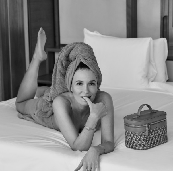 Luxury hotel lifestyle photography featuring a woman with towel wrapped hair relaxing on bed in monochrome.