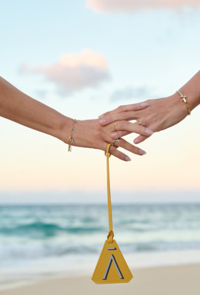 Elegant jewelry showcasing gold bracelets and rings with stylish accessories at the beach during sunset.