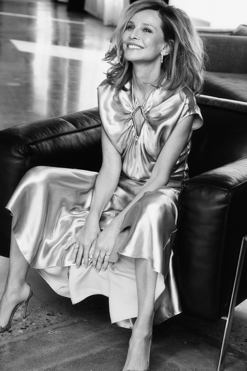 Elegant woman in satin dress sitting on leather sofa, black and white portrait by Pamela Hanson Photography.