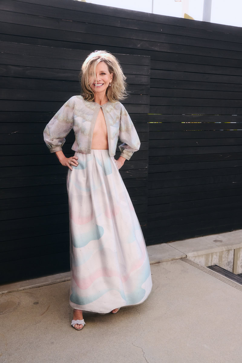 Elegant woman in pastel-colored designer gown and shimmering bolero jacket, standing outdoors against modern black wooden wall - fashion photography by Pamela Hanson.