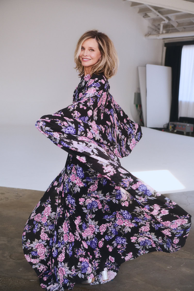 Vibrant floral dress worn by a smiling woman in a professional photography studio for fashion and portrait photography.