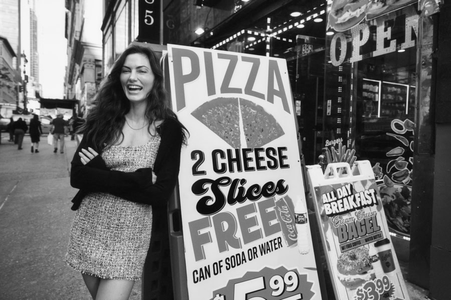 Girl laughing on city street near pizza sign, urban lifestyle photography, street scene, candid moment, black and white image, Pamela Hanson Photography.