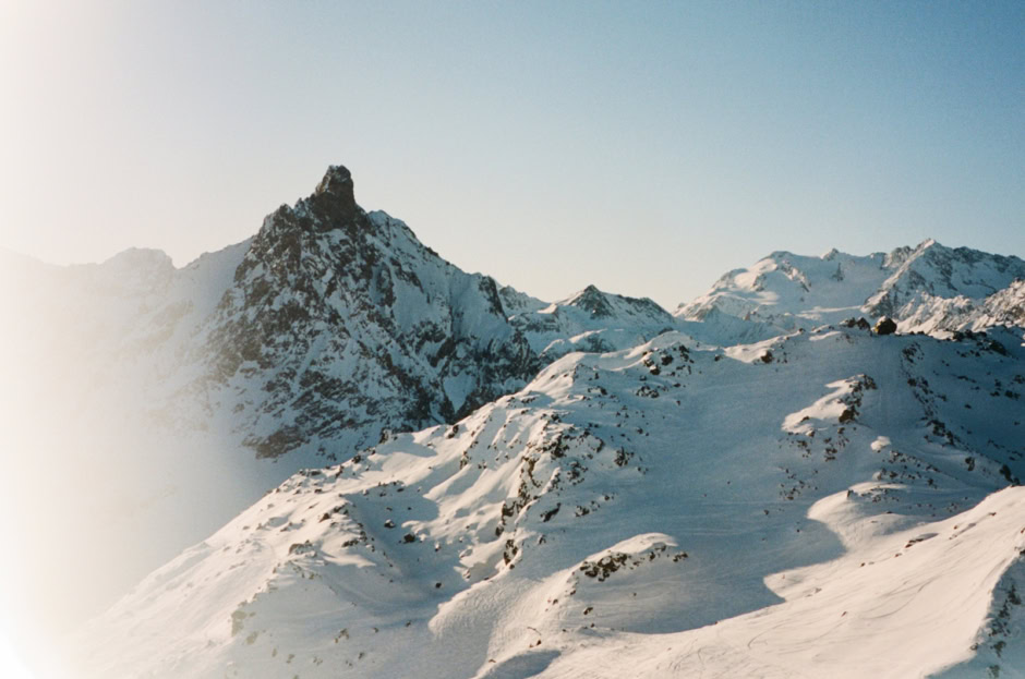 Snow-covered rugged mountain landscape in the Alps with sharp peaks and a clear blue sky, captured by Pamela Hanson Photography.