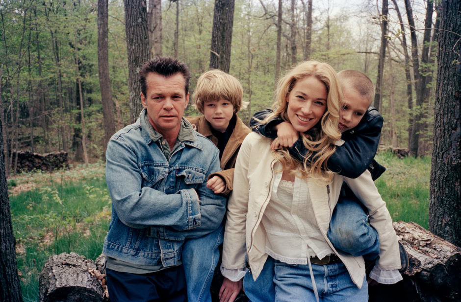 Family portrait in the woods, outdoor photography of a father, mother, and two children, natural light, candid shot, emotional family moment, Pamela Hanson Photography, professional family photographer, nature setting with trees and greenery.