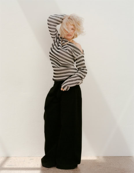 Elegant fashion portrait of a woman in black wide-leg pants and a striped sweater, showcasing sophisticated portrait photography by Pamela Hanson.
