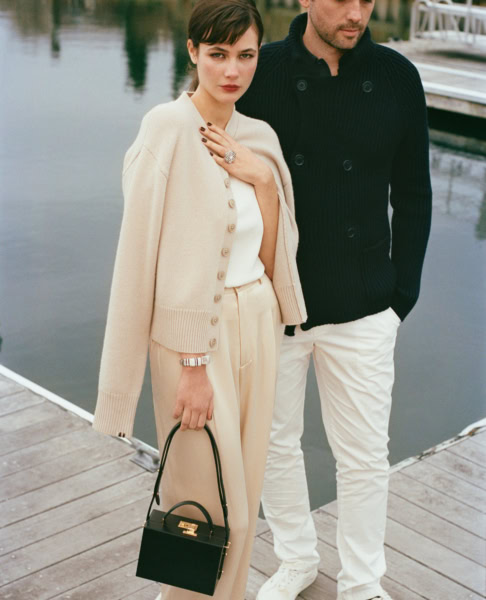 Luxury fashion portrait of a woman and man by Pamela Hanson, sophisticated style, elegant clothing, waterfront setting, editorial photography, timeless fashion photography, woman holding designer handbag, upscale lifestyle image.