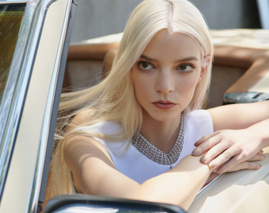 Elegant blonde woman in a white top with a pearl necklace sitting in a vintage car, showcasing luxurious fashion and timeless style. Perfect for high-end fashion, glamour photography, and lifestyle visuals.