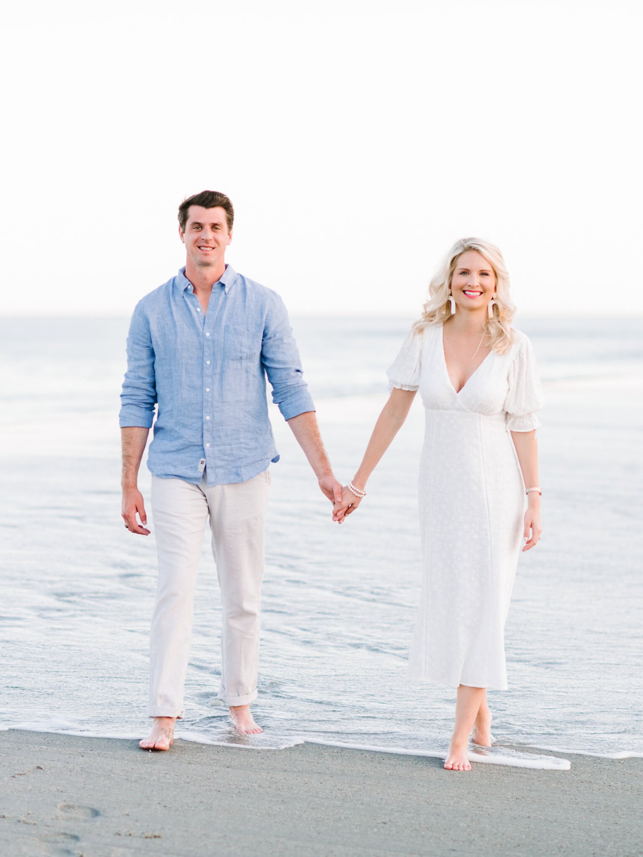 Engagement photo in Myrtle Beach of a couple walking barefoot along the shoreline with soft coastal light
