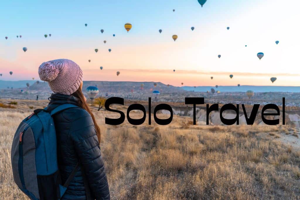 woman starting out over hill looking at hot air balloons