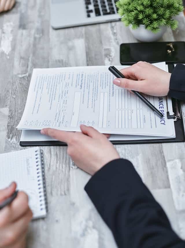Insurance forms on a clipboard wirh hands holding clipboard