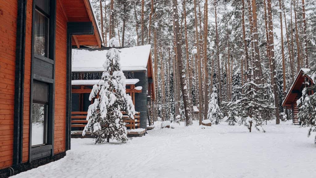 A cozy wooden cabin nestled in a snow-covered forest during wintertime.