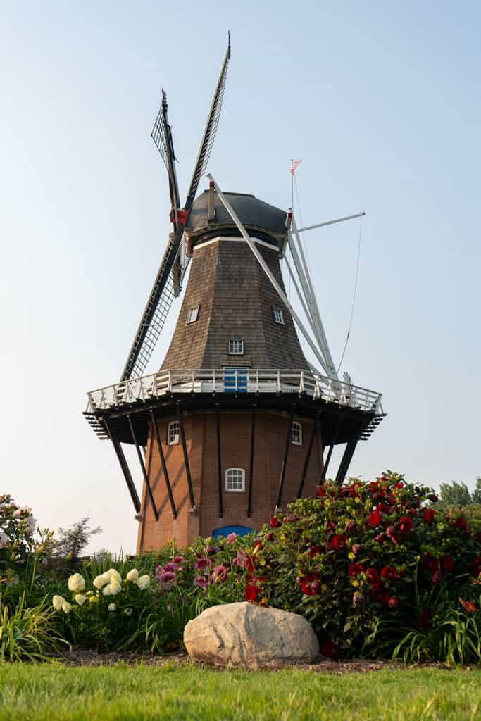 A picturesque Dutch windmill surrounded by vibrant flowers in Holland, Michigan's summer landscape.
