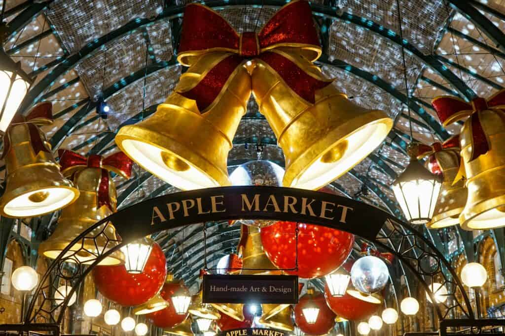 big gold christmas bells hanging over christmas decorations with a sign that says apple market