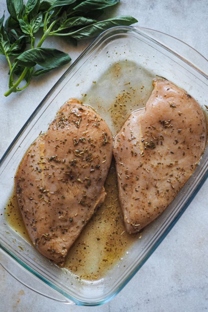 Esta receta de Pechugas de Pollo Caprese es una deliciosa variación de la clásica ensalada italiana! El marinado sirve para que las pechugas queden con más sabor y más tiernas. En esta foto vemos las pechugas de pollo en una fuente de cristal embadurnadas con el marinado de hierbas y vinagre balsámico.