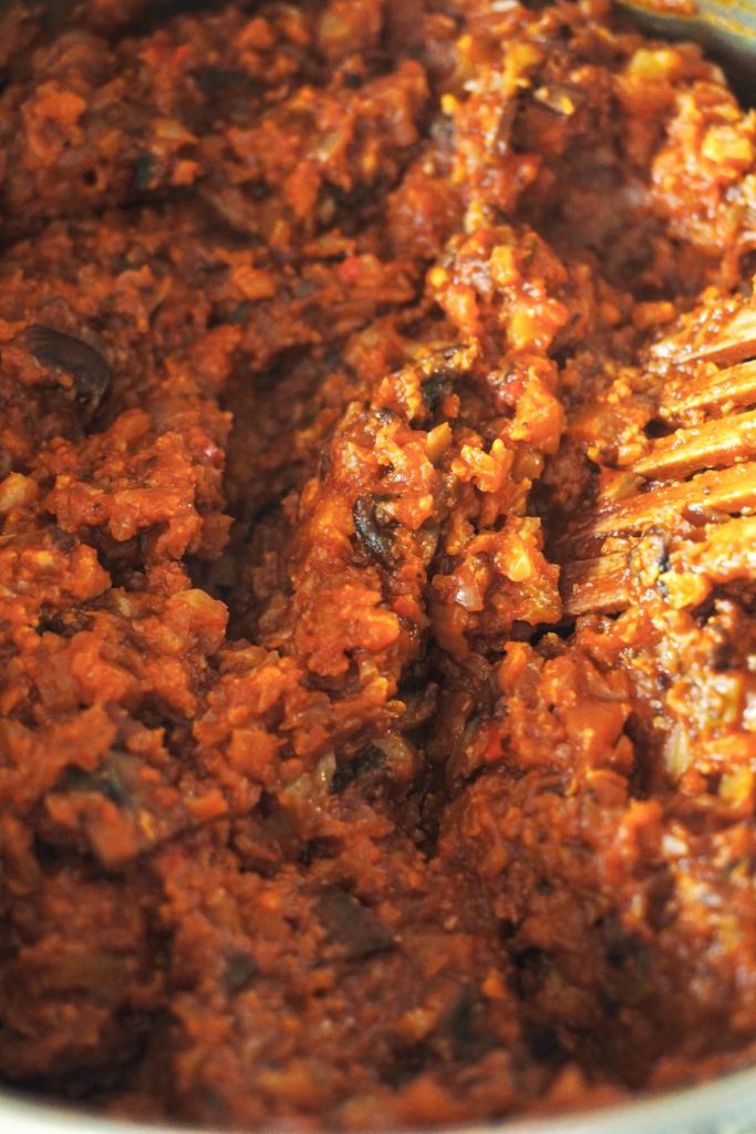 No tienes que ser vegetariano ni vegano para enamorarte de estos Espaguetis con Boloñesa de Coliflor, porque es tan sustanciosa que solo por el sabor y texturas ya te quedarás boqueabierto. Es una receta perfecta para introducir un poco de verduritas a la dieta sin uno darse cuenta. ¿Y que tienes una cena con amigos veganos? ¡Pues esta es la tuya para triunfar! En esta foto se ve la salsa boloñesa de coliflor de muy cerca con una pala de madera dentro.