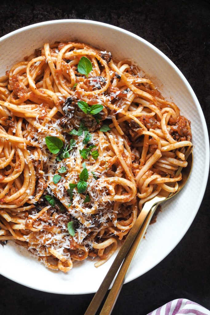 No tienes que ser vegetariano ni vegano para enamorarte de estos Espaguetis con Boloñesa de Coliflor, porque es tan sustanciosa que solo por el sabor y texturas ya te quedarás boqueabierto. Es una receta perfecta para introducir un poco de verduritas a la dieta sin uno darse cuenta. ¿Y que tienes una cena con amigos veganos? ¡Pues esta es la tuya para triunfar! En esta foto se ve un plato de espaguetis con boloñesa de coliflor y decorados con parmesano y orégano.