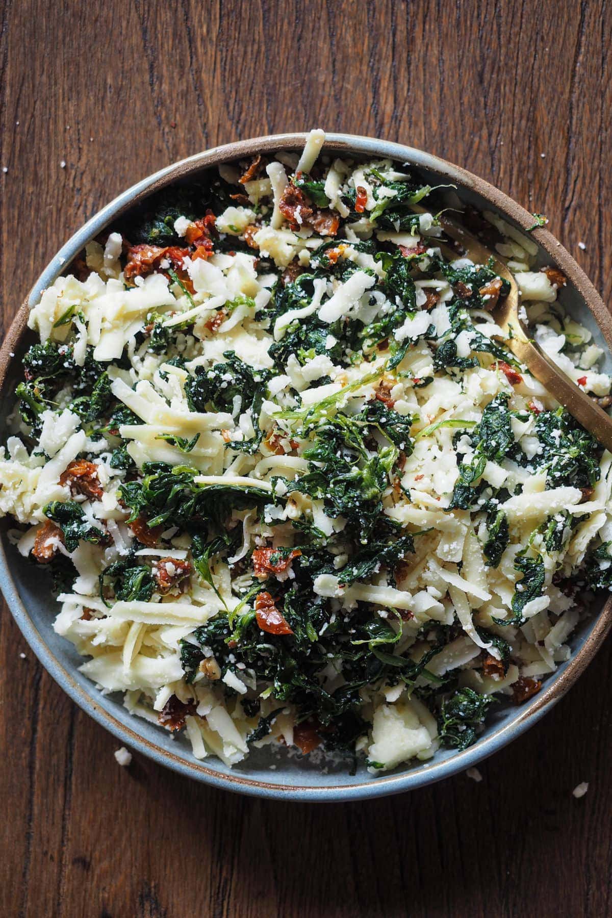 Ingredientes necesarios para el relleno de la Quesapita de Espinacas y Tomate Seco Ingredientes o Sandwich de Queso Espinacas y Tomate Seco con Pita: tomate seco, espinacas, mucho queso y un poco de chile. Todos los ingredientes están mezclados en un plato.