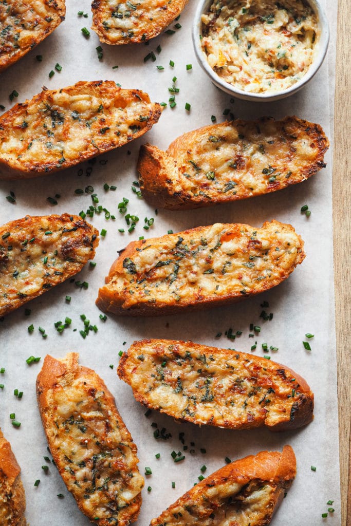 Pizza Style Garlic Confit Bread is a real crowd-pleaser. Good butter is mixed with fresh herbs, sundried tomato, cheese, and garlic. But not your average roasted garlic, confited garlic instead. It provides a gentle garlic flavour, so don't be afraid about your breath afterwards! It's perfect as an appetiser or side to accompany your soups and salads, your choice, but in any case, it will knock your socks off. | Paula's Apron Recipe