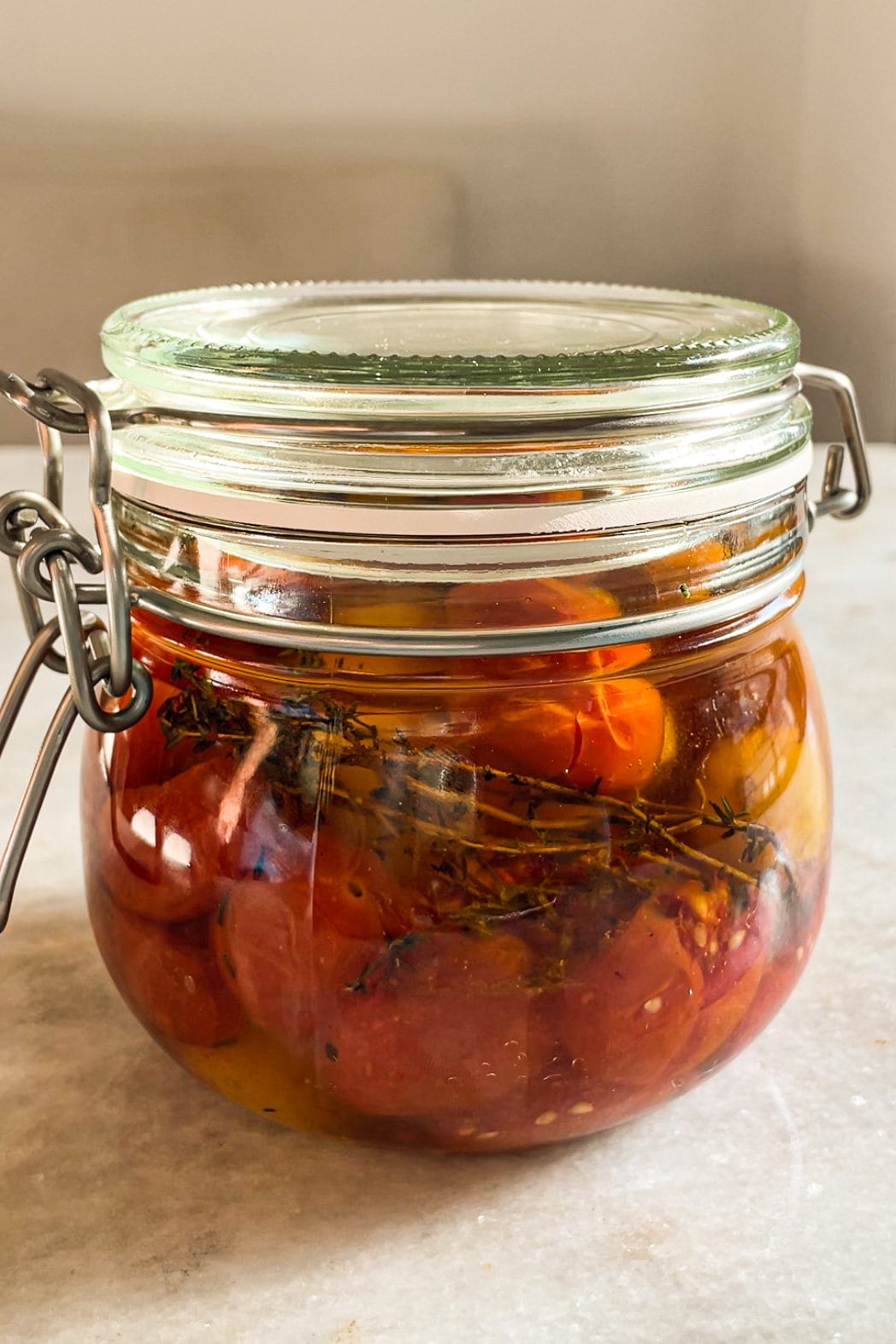 El Tomate Confitado (o Confit de Tomate) es mi forma favorita de conservar el verano. Solo necesitas 5 minutos como máximo de preparación y el resto lo hace el horno. El resultado es un tomate potenciado de sabor, jugoso y dulzón ideal para dar un toque especial y alegrar una infinidad de platos. Lo puedes usar sobre tostadas, con pasta, como topping de untables, carne, pescado, en bocadillos… Hoy le he añadido chalotas, ajo y tomillo pero puedes usar los aromatizantes que más te gusten. En cualquier caso, el aceite infusionado que te va a quedar será delicioso y podrás aprovechar hasta la última gota. | Receta de Paula's Apron