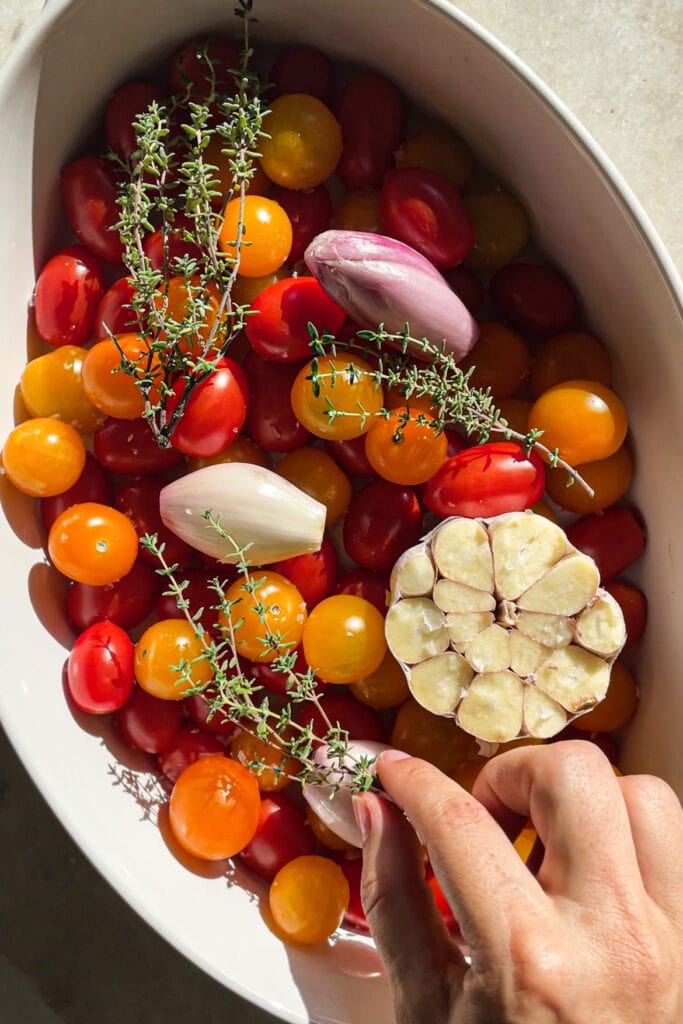 El Tomate Confitado (o Confit de Tomate) es mi forma favorita de conservar el verano. Solo necesitas 5 minutos como máximo de preparación y el resto lo hace el horno. El resultado es un tomate potenciado de sabor, jugoso y dulzón ideal para dar un toque especial y alegrar una infinidad de platos. Lo puedes usar sobre tostadas, con pasta, como topping de untables, carne, pescado, en bocadillos… Hoy le he añadido chalotas, ajo y tomillo pero puedes usar los aromatizantes que más te gusten. En cualquier caso, el aceite infusionado que te va a quedar será delicioso y podrás aprovechar hasta la última gota. | Receta de Paula's Apron