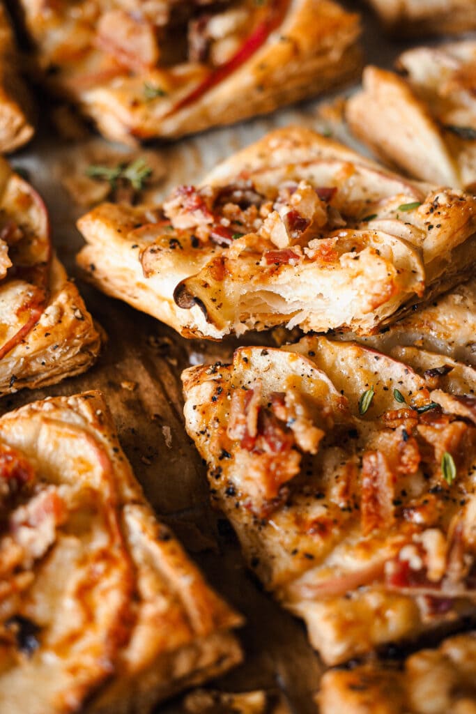 Estos Hojaldritos de Manzana con Panceta y Cheddar son un aperitivo ideal durante otoño e invierno. Mezclan a la perfección dulce y salado, con la manzana de temporada que tan bien le va a la panceta. Y te sorprenderá la combinación, pero un toque de cheddar maduro queda de maravilla, con su punto de sabor un poco salado pero sin ser demasiado fuerte. Son fáciles de hacer y solo llevan 5 ingredientes, ¡simplemente perfectos! | Receta de Paula's Apron