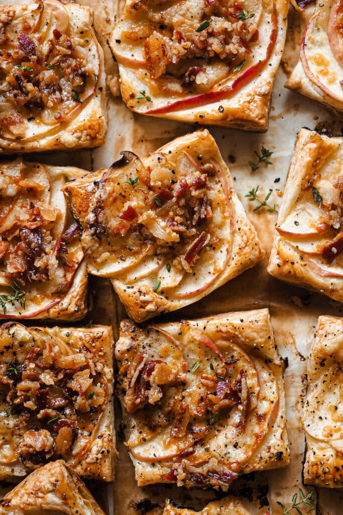 Estos Hojaldritos de Manzana con Panceta y Cheddar son un aperitivo ideal durante otoño e invierno. Mezclan a la perfección dulce y salado, con la manzana de temporada que tan bien le va a la panceta. Y te sorprenderá la combinación, pero un toque de cheddar maduro queda de maravilla, con su punto de sabor un poco salado pero sin ser demasiado fuerte. Son fáciles de hacer y solo llevan 5 ingredientes, ¡simplemente perfectos! | Receta de Paula's Apron