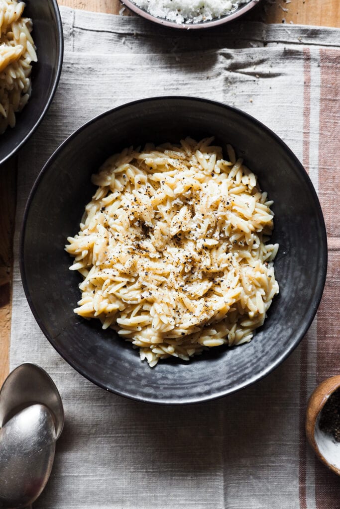 Esta receta de Orzo Cacio e Pepe (Orzotto Cacio e Pepe o Falso Risotto de Orzo con Queso y Pimienta) combina los sabores del clásico plato de pasta romano con la textura de un risotto quedando increíblemente bueno y lo mejor de todo es que es fácil y rápido de hacer: se hace todo en una sartén o cazuela sin necesidad de ir removiendo el orzo y todo el caldo se echa de golpe. Para la próxima cena o comida que tengas a tu cargo y en la que quieras impresionar sin complicarte nada, este Orzo Cacio e Pepe es tu receta. | Receta de Paula's Apron