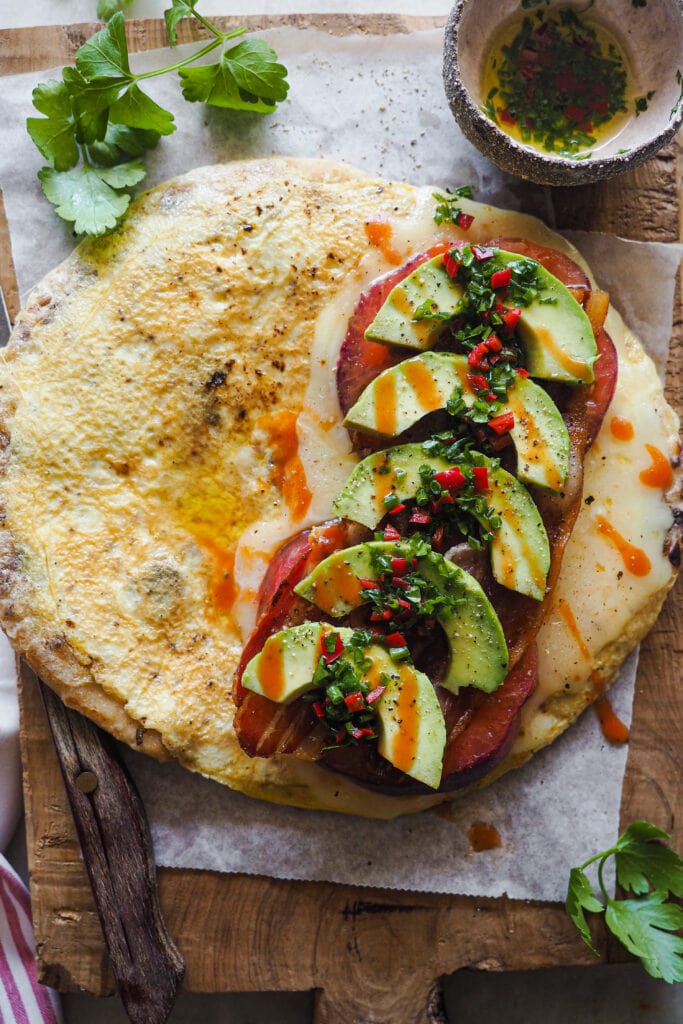Este Bocadillo de Tortilla con Pan Naan, Queso, Aguacate, Tomate y Bacon es súper completo. Queda jugoso y sabroso y lo tienes listo en 10 minutos. Va bien tanto para desayuno o brunch como para una comida o cena rápida y queda buenísimo. Si uno te parece grande, siempre lo puedes partir por la mitad y quedarte con una, aunque te aseguro que a la que le pegues un mordisco no querrás compartir nada. | Receta de Paula's Apron